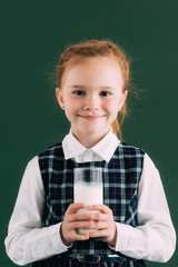 adorable little schoolgirl holding glass of milk and smiling at camera © LIGHTFIELD STUDIOS