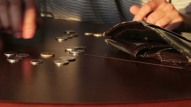Poor guy counting up small metal money on the table