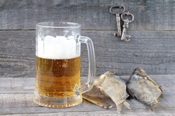 A mug of  light beer and dry fish on a wooden background.