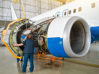 Concept maintenance of aircraft. Replacing the engine on the airplane, working people tap. © aapsky