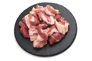 Pieces of fresh pork meat on stone plate, isolated on white background. Close-up.