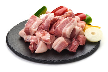 Pieces of fresh pork meat sliced vegetables on stone plate, isolated on white background. Close-up.