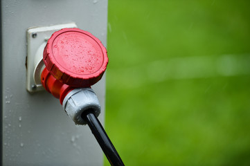 Raindrops are seen on industrial electric plug during heavy rain