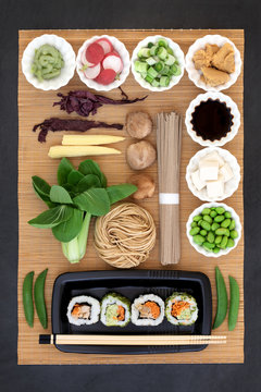 Japanese macrobiotic health food with sushi, wasabi paste, tofu, vegetables, soba noodles, miso paste, soy, with foods high in omega 3, protein, antioxidants, fibre, vitamins and minerals. On bamboo.