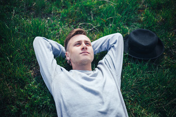 young man lying on grass hat near