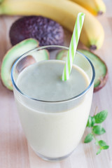 Smoothie with avocado, banana, milk and honey on wooden background, vertical