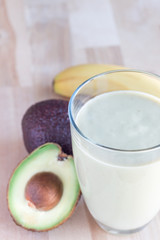 Healthy smoothie with avocado, banana, milk and honey on a wooden background, vertical, copy space