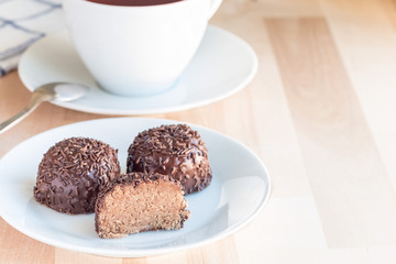 Swedish sweets Arrack balls, made from cookie crumbs, cocoa, butter and coconut wine Arrack flavour, on wooden table with cup of tea, horizontal, copy space
