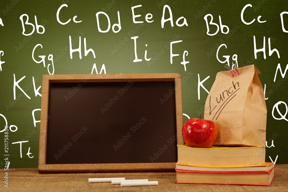 Poster composite image of slate with chalks by lunch bag and books on