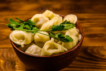Fresh dumplings in ceramic bowl on wooden table