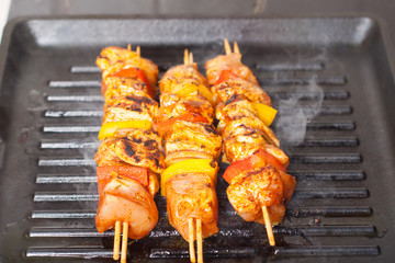 Preparation of chicken skewers with vegetables on iron grill pan