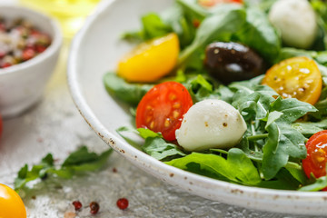 Fresh summer salad with arugula, yellow and red cherry tomatoes, Kalamata olives and mozzarella