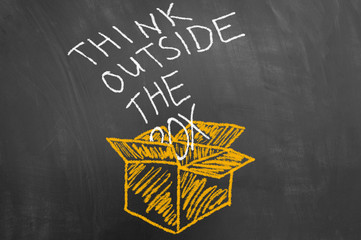 Think outside the box concept with text on blackboard.