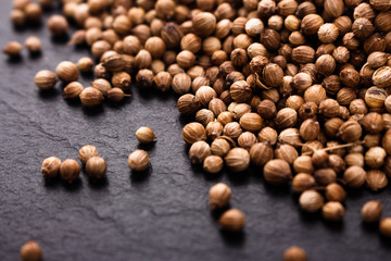 coriander seeds on a dark stone background, essential oil