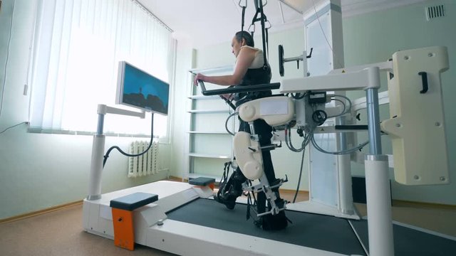Modern medical recovery device. Training process of a physically challenged man on a walking simulation system