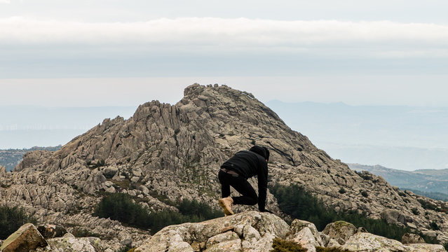 Ein Mann klettert auf dem Monte Limbara auf Sardinien und blickt &uuml;ber die Kante in den Abgrund