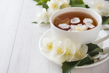 Mug of herbal tea with petals of Jasmine flowers on a light background. Copy space