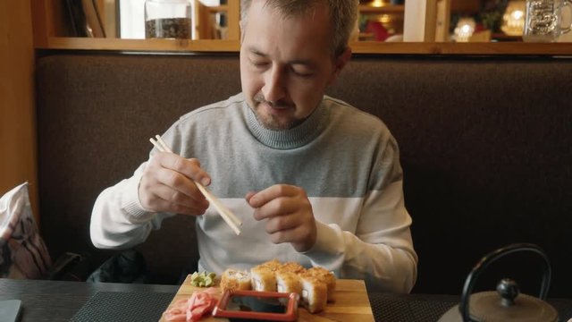 A man learns to use chopsticks for sushi. Hashi, chopsticks ohashi, varibasi - simple wooden hasi