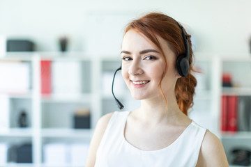 Naklejka premium Beautiful young girl in headphones with microphone standing in office.