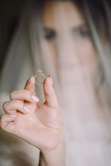Mysterious portrait of a bride hidden under the veil and holding a wedding ring