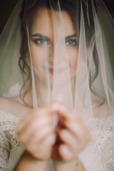 Mysterious portrait of a bride hidden under the veil and holding a wedding ring