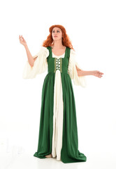 Naklejka premium full length portrait of red haired girl wearing long green medieval gown. standing pose, isolated on white studio background.