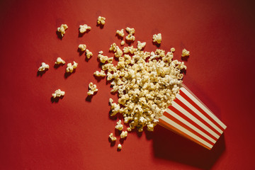 Spilled popcorn on a red background, cinema, movies and entertainment concept