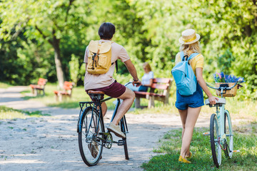 back view of couple with retro bicycle in park on summer day