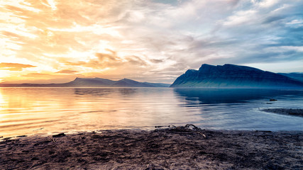 the nature of the fire and ice beautiful bright yellow of the sunset and the mountain with the shadow blue color on the background of water