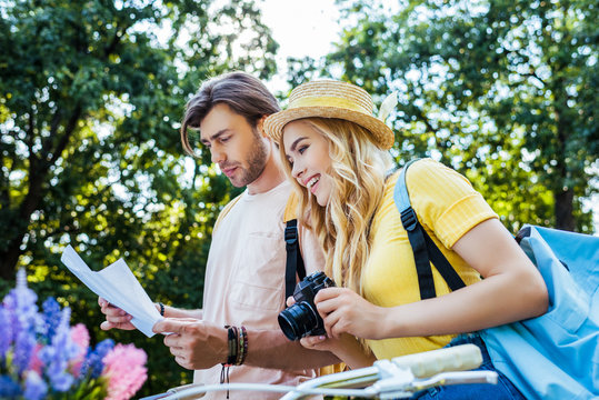 side view of couple of tourists with map and photo camera in park