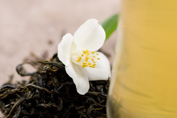 A flower of jasmine and dried leaves of green tea.