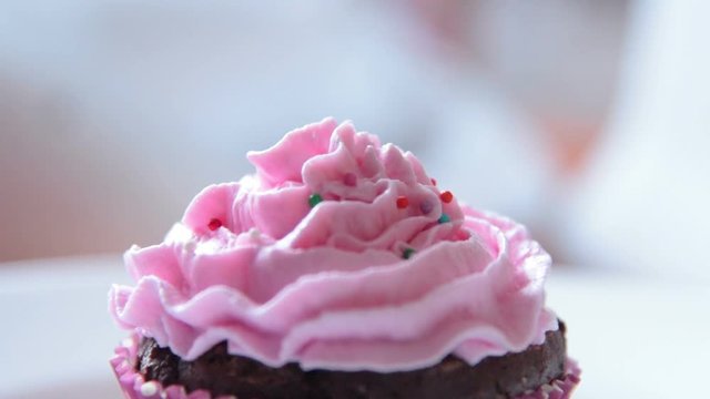Close-up shot of decorating cupcake with colourful sugar beads