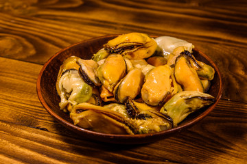 Ceramic plate with prepared mussels on wooden table