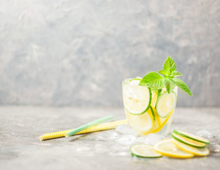 A refreshing cocktail of lemon lime and mint leaves with ice in a glass goblet on a gray background. Summer drink lemonade. Selective focus. Copy space