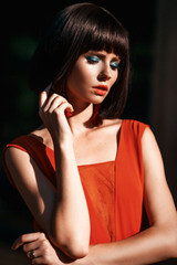 Beautiful close up portrait in retro vintage style of toyng woman in fashion earrings and long drees. Bright colorful make up and stilysh haircut. Outside street photo.