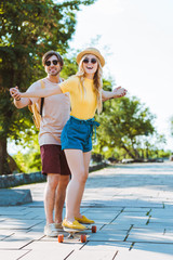 Naklejka premium man helping girlfriend skating on longboard on street