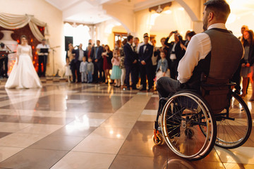 Bride and groom on the wheelchair dance for the first time in the restaurant hall