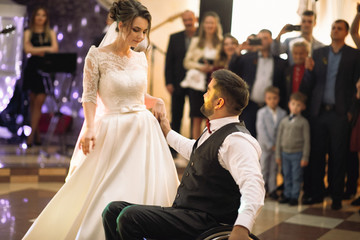 Bride and groom on the wheelchair dance for the first time in the restaurant hall