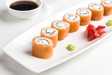 Japanese sushi rolls with salmon, serving with soy sauce, wasabi and ginger on white background