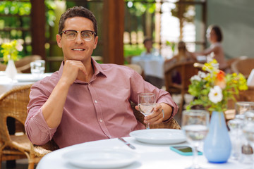 Delicious dinner. Graceful smiling man wearing pink shirt and black glasses having delicious dinner