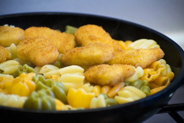 Pasta with chicken nuggets in a frying pan. Fried Chicken Nuggets. Tasty, crispy chicken nuggets. Children's menu.