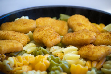 Pasta with chicken nuggets in a frying pan. Fried Chicken Nuggets. Tasty, crispy chicken nuggets. Children's menu.