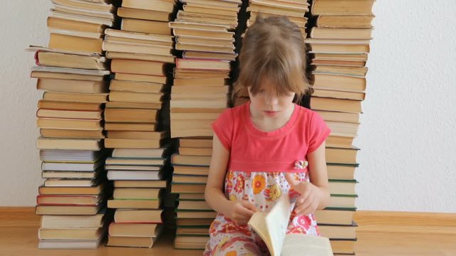Little girl paging a book sitting on the floor