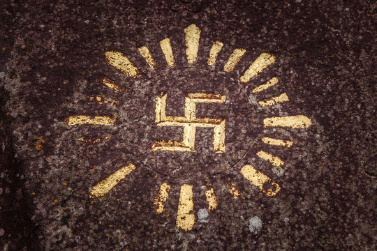 Swastika carved and drawn on a rock - an ancient solar hinduism symbol in the Indonesian culture