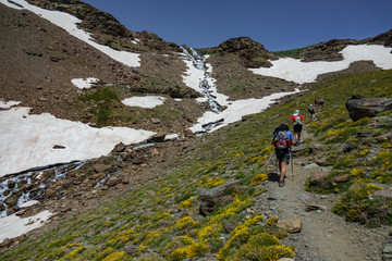 Fototapeta premium Hikers ascending mountain with waterfall
