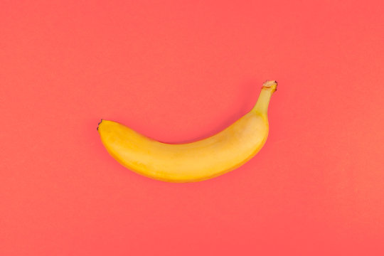 toy yellow plastic banana on red colored background