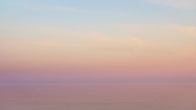 Majestic sunset in pastel tones over calm water. Looped seamless video.