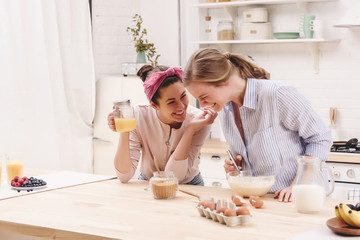 Two cheerful friends cook together desserts and gossip in the kitchen