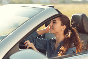 Fototapeta na wymiar young girl driving cabrio car, on sunset light