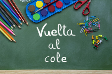 Letras de vuelta a la escuela escritas con tiza blanca en una  pizarra verde con materiales...